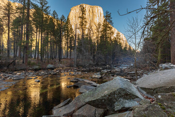 Winter view of the swirling Tuolumne river with huge river rocks, El Capitan marble mountain  in Yosemite Park, California.