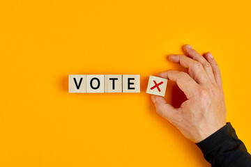 Concept of voting no or negative vote. Male hand placing wooden cube with no symbol next to the cubes with the word vote.