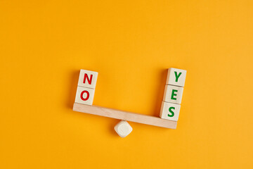 es and no inscription on wooden cubes on a seesaw with yes outweighs no