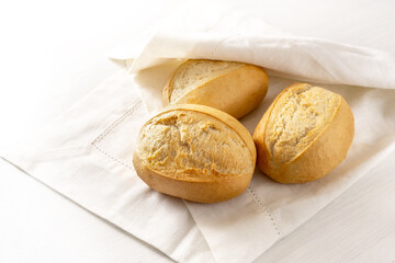 Fresh bread rolls or buns in a white napkin for breakfast on the table, copy space