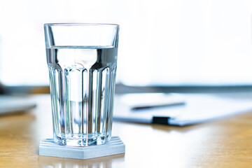 Purity of drinking water in a glass on table close up with copyspace. Healthcare and work life balance in everyday life. Mineral drinking water in a glass close up. Relaxing and refreshing concept.