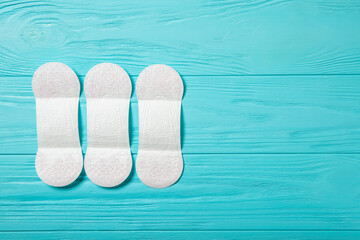 Women's pads and on a blue wooden background. Top view, place for text.