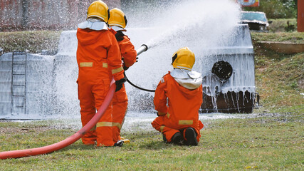 Firefighter fighting with flame using fire hose chemical water foam spray engine. Fireman wear hard...