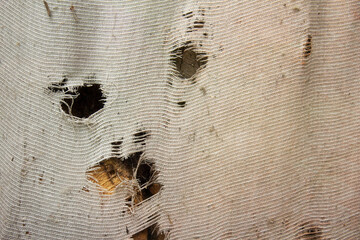 A wooden window with an old shabby curtain. Old, dirty, vintage texture. Appearance.