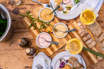High angle view of a selection of taramasalata and hummus dips with freshly baked bread, served on a vintage table with fresh apple juice and white wine