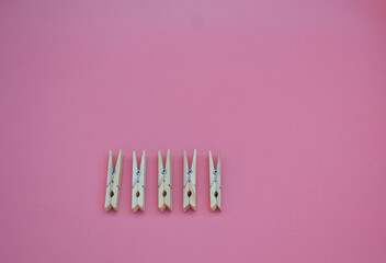 simple wooden clothespins scattered on a pink background