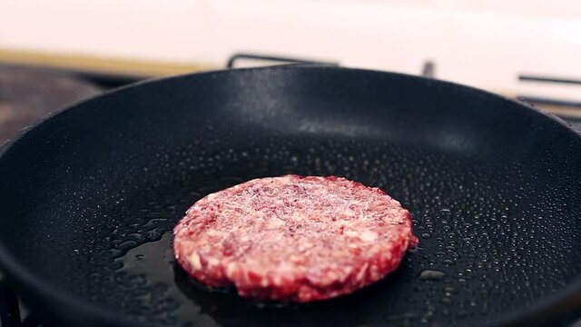 Footage of raw uncooked minced meat frying on hot pan in close up.Delicious beef cutlet cooking in home kitchen for traditional burge dish.Natural & healthy patty for hamburger preparation