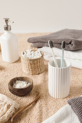 Beauty health care composition with ear sticks in rattan casket, towel, powder, toothbrushes, liquid soap on beige towel. Female beauty treatment routine concept