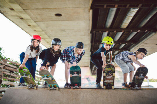 Extreme sport in city. Skateboarding Club for children. Group friends posing on ramp at skatepark. Early adolescence in skate training. Friends skateboarders on street platform for skating on board