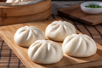 Delicious baozi, Chinese steamed meat bun is ready to eat on serving plate and steamer, close up, copy space product design concept.