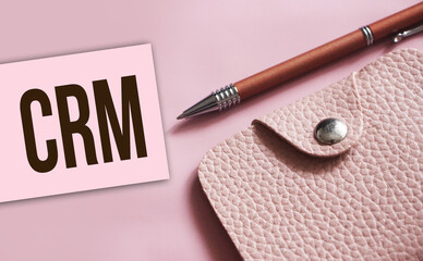 CRM abbreviation written on a business card, pen and beige leather wallet. Financial business...