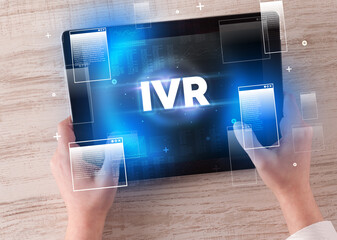 Close-up of a hand holding tablet with IVR abbreviation, modern technology concept