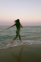 Young woman practicing yoga on the beach during sunset. Stock photo of a girl exercising on the Mediterranean sea.