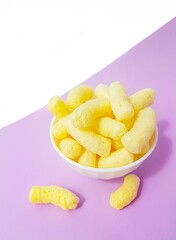 Yellow corn sticks in a white plate on a purple background.