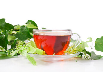 Linden tea in a transparent cup with linden buds and leaves isolated on a white background.