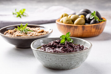 Tapenade - paste made from olives. Bowls with spreadable black and green olive cream on concrete...