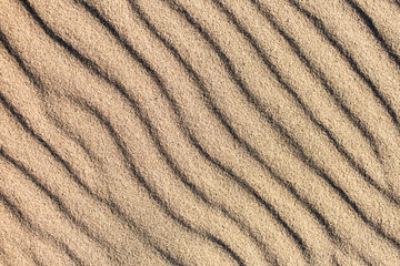 Fototapeta na wymiar Natural sand pattern, interesting abstract texture. Waves on a sand.