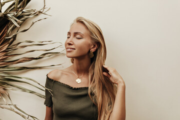 Charming pretty woman in khaki top smiles with closed eyes. Blonde young lady in dark green t-shirt...