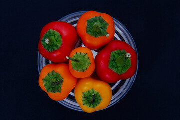 A variety of colorful and chopped red and yellow vegetables and fruits with a black background.