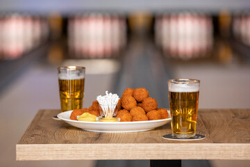 Bitterballen with mustard at a bowling alley with a beer that is being grabbed