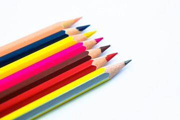 Some different colored wood pencil crayons scattered across a white background