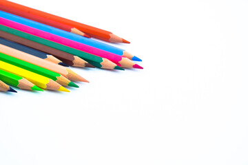Bunch of different colored wood pencil crayons placed in a pile on a white background