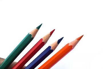 Fototapeta premium Four different colored wood pencil crayons scattered on a white background