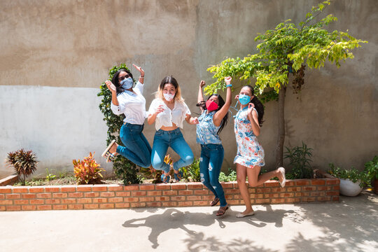 Portrait of a group of women with a jumping face mask. Multiracial women of different sizes jumping looking at the camera and smiling.