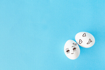Couple eggs with happy face for love concept, blue background with empty space