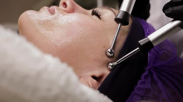 The beautician performs the microcurrent procedure in the beauty salon. The procedure stimulates collagen production, lifting, fights wrinkles, facial muscle tone, lymphatic drainage.