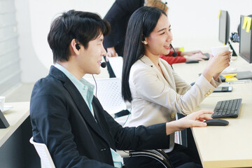 Fototapeta premium Smiling of Business people Call Center and technical Support staff. Receptionist phone operators teamwork relax and drinking coffee. Asian customer support team.