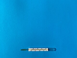 Glass mercury thermometer on a blue background