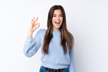 Obraz premium Teenager girl over isolated white background surprised and showing ok sign