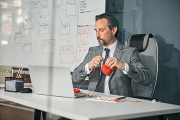 Attentive man knitting while sitting at the desk