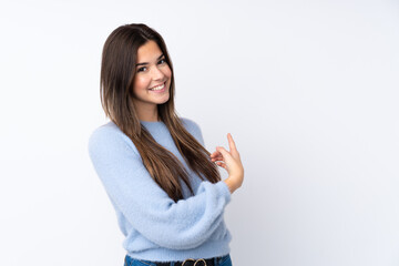 Teenager girl over isolated white background pointing back