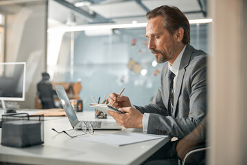 Professional creative director wearing grey suit sitting at the white table
