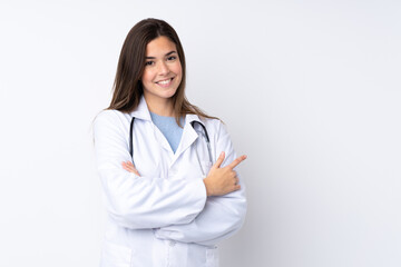 Teenager girl over isolated white background wearing a doctor gown and pointing side