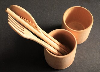 Bamboo wood cutlery, disposable fork, spoon and knife made of natural material on black background.