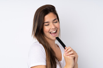 Teenager girl over isolated background with hair comb and singing