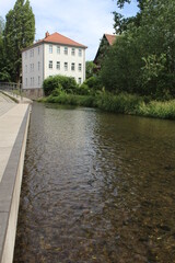 Fototapeta na wymiar Transparent water of the river Gera running through Erfurt, in Germany, and reflecting a German house. 