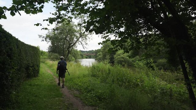 A man walking beside a river in England