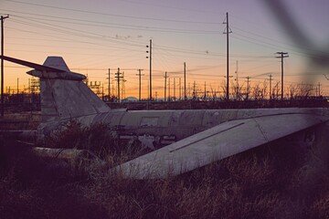Old plane lying on the ground with the electrical grid behind it.