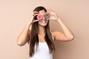 Teenager girl over isolated background holding donuts in eyes