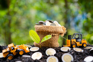 Financial business investment concept. A sack of bags filled with coins filled out on the mound and a crane model was loading and seedlings.