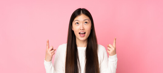 Young asian woman over isolated background surprised and pointing up