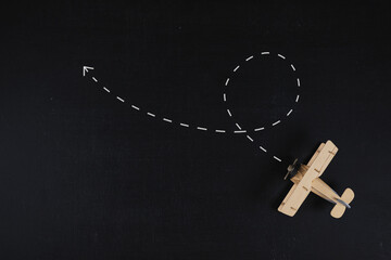 Travel destination concept. A wooden airplane model placed on a black board ground