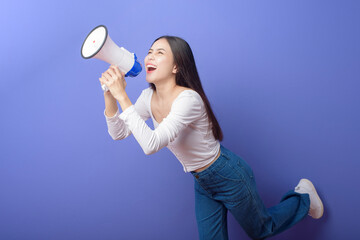 portrait of young beautiful smiling woman is using megaphone to announce over isolated purple...