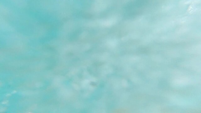 Underwater shot of young man diving into the sea. Having fun on beach summer holidays vacation enjoying recreational leisure time swimming in sea. A man swims underwater in the sea with his eyes open