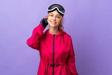 Skier teenager girl with snowboarding glasses over isolated purple background laughing