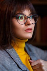 Beautiful dreamy girl in stylish sharp glasses. In the library.